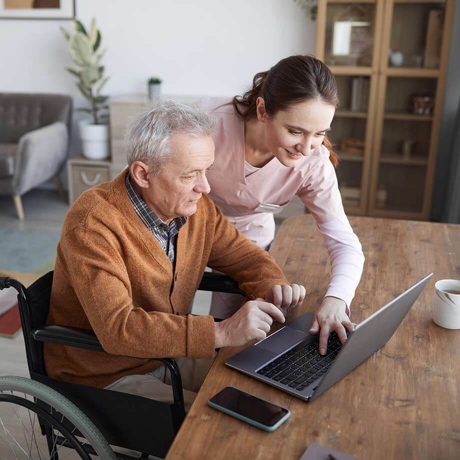 Community support coordination worker helping man use his laptop