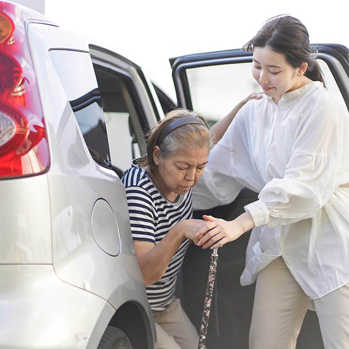 Core support worker helping frail women out of a car.