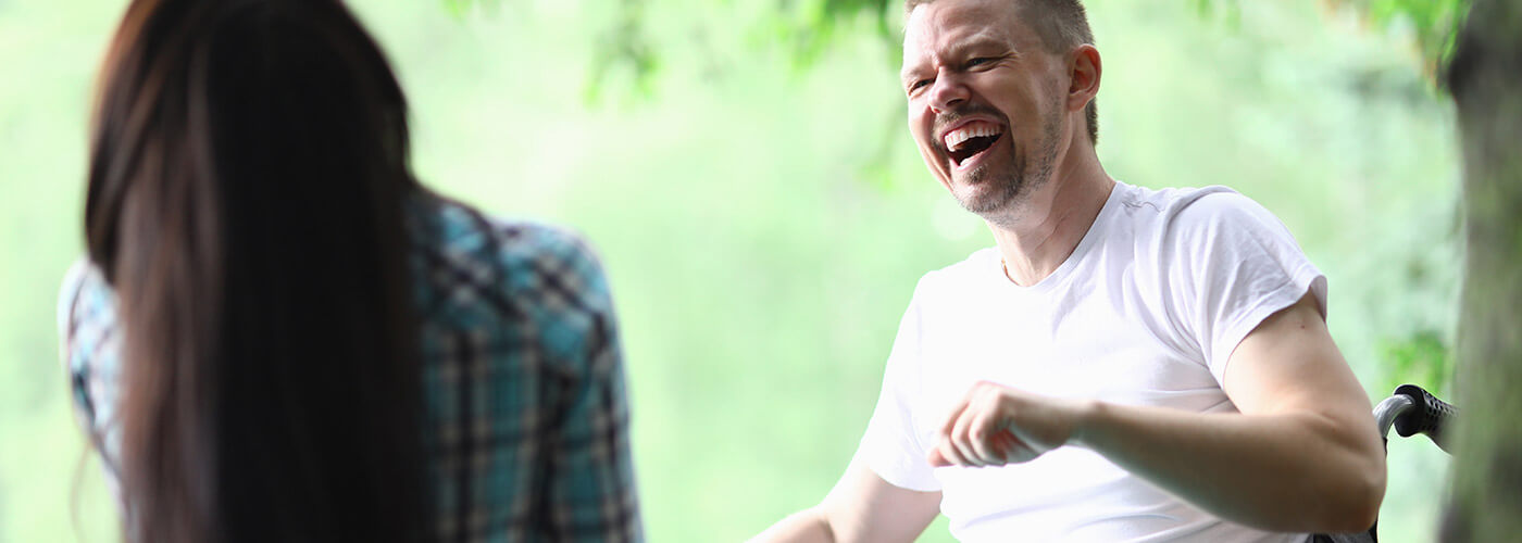 Man in a wheelchair laughing with his ndis support services coordinator.