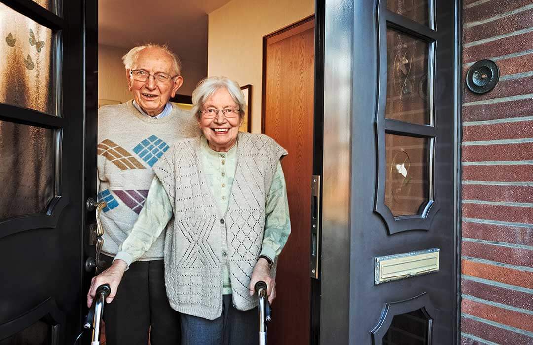 Elderly couple standing in their doorway.