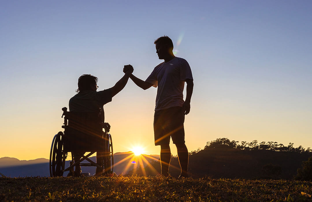 Your Own Way Support coordinator shaking hands with NDIS participant in wheelchair.